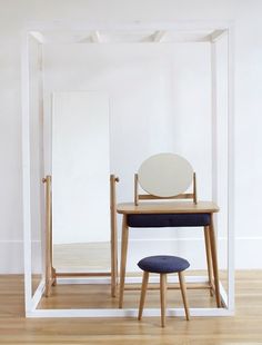 a chair sitting in front of a mirror on top of a wooden floor next to a table