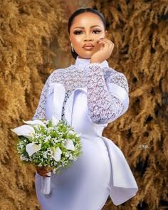 a woman in a white dress holding a bouquet of flowers and posing for the camera