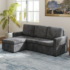 a gray couch sitting on top of a rug in a living room next to a window