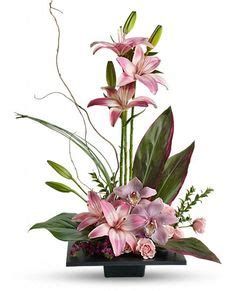 an arrangement of pink flowers and greenery in a black vase on a white background