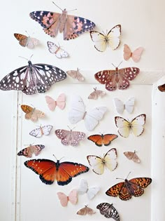 a group of butterflies hanging from the side of a white wall next to a door