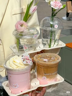 a person holding two trays with ice cream and flowers