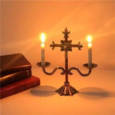 a candle holder with three lit candles on it next to an open bible and a book