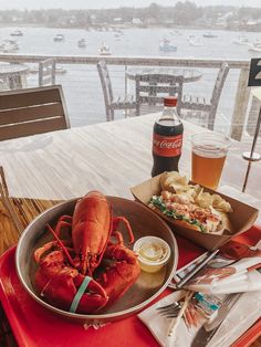 lobster and chips on a red tray at a restaurant table with a view of the water