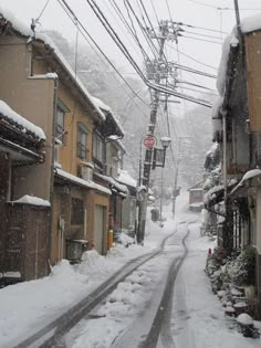 a snow covered street with power lines above it and buildings on both sides in the distance