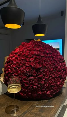 a wine glass sitting on top of a wooden table next to a large flower ball