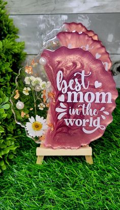 the best mom in the world award is displayed on some green grass with daisies