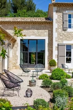 an outdoor patio with chairs and tables in front of a house