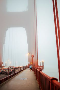 cars are driving across the bridge on a foggy day