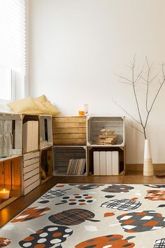 a living room with an area rug, bookshelf and vase on the floor