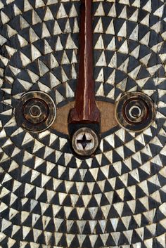 an intricately designed wooden door with metal knobs on it's face and eyes