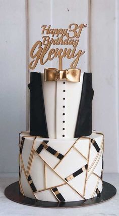 a white and black birthday cake with gold accents