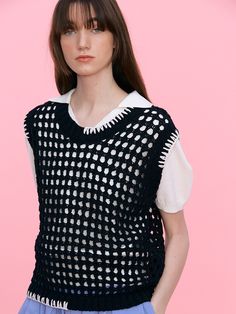 a model wears a black and white sweater with polka dots on the top, while wearing blue pants