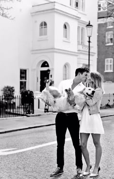 a man and woman standing on the side of a road with two dogs in their arms