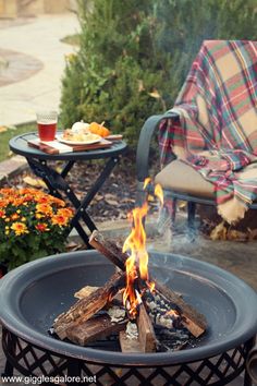 a fire pit sitting on top of a patio next to a table with food and drinks