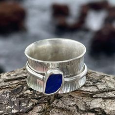 a silver ring with a blue stone in the middle on top of a tree branch