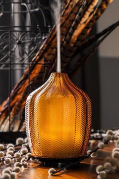 a yellow vase sitting on top of a wooden table next to some white balls and branches