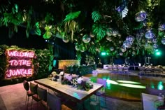 an outdoor party with lights and decorations on the ceiling, tables set up in front of them