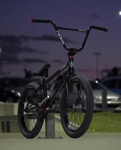 a black bicycle is parked on the side of a road at night with cars in the background