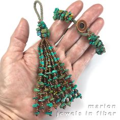 a hand holding a green and brown beaded christmas tree ornament in it's palm