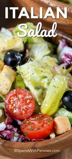 a salad in a wooden bowl with tomatoes, lettuce and olives