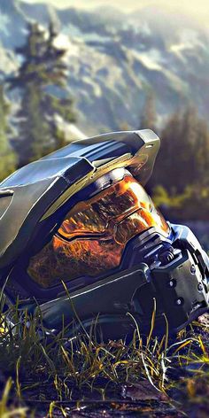 a motorcycle helmet sitting on the ground with mountains in the backgrouds behind it