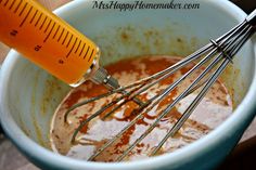 a whisk is in a bowl with some sauce and an orange thermometer