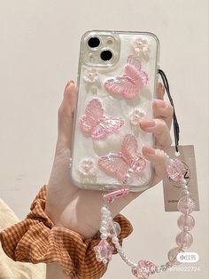 a woman holding up a phone case with pink butterflies on it and pearls around the edges