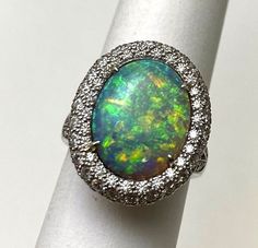 "This gorgeous Richard Krementz Opal and Diamond ring is crafted in luxurious platinum.. Richard Krementz was known for cutting and setting some of the world's finest gemstones. This one is truly a gem!  Featured is a genuine opal that emits an array of rainbow flashes, primarily blue and green with bright flecks of red and yellow. It is an oval cut opal estimated to be 4.50ct. A triple row of bead set round brilliant cut diamonds surround the ring and carry onto the shoulders and undercarriage Wide Engagement Ring, Opal And Diamond Ring, Estate Rings, Bead Set, Red And Yellow, Heart Locket, Diamond Heart, Round Brilliant Cut Diamond, Quality Diamonds