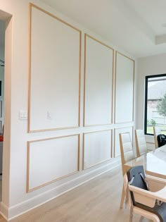 a dining room with white walls and wood trim around the windows, along with chairs