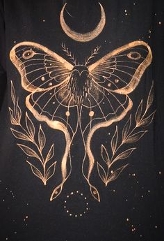 a black shirt with a gold butterfly on it's chest and the moon in the background