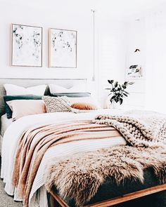 a bedroom with white walls, pink and gray bedding, two pictures on the wall