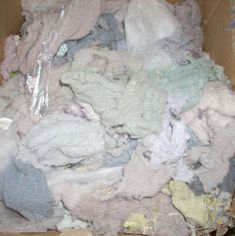 a cardboard box filled with lots of different colored clothes and other things in the background