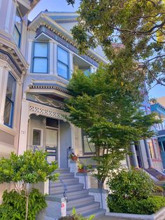 a house that is painted blue and has stairs leading up to the front door with trees on both sides