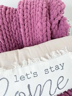 a pile of pink towels sitting on top of a white pillow that says let's stay home