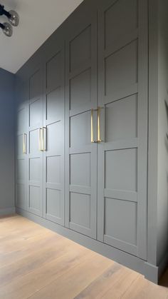 an empty room with wooden flooring and gray painted cupboards on the side wall