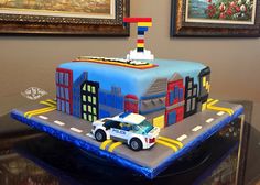 a cake that is shaped like a police car on top of a street with buildings