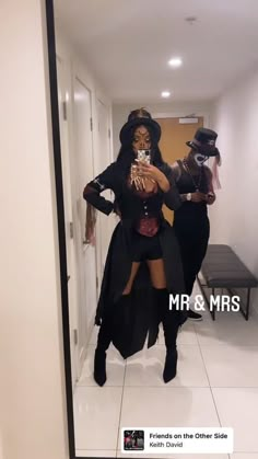 two women dressed up in costumes taking a selfie with their cell phone while standing in a hallway