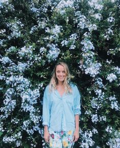 a woman standing in front of blue flowers