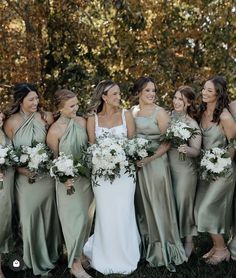 a group of women standing next to each other holding bouquets in their hands and smiling