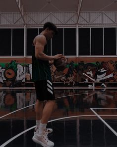 a young man standing on top of a basketball court holding a ball in his hand