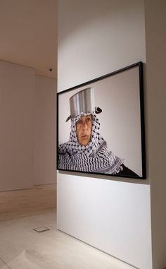 an old man wearing a chef's hat in front of a painting on the wall