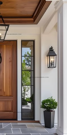 a large wooden door with two lanterns on the side and potted plants next to it