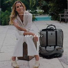 a woman sitting on top of a suitcase next to a bag