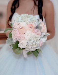 a bride holding a bouquet of pink and white flowers