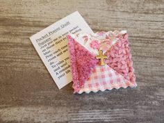 an origami cross on top of a pink and white checkered paper folded in half