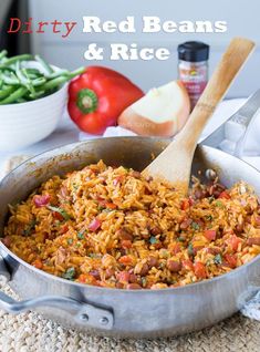 red beans and rice in a pan with a wooden spoon next to it on a table