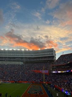 a football stadium filled with lots of people watching the sun go down on it's field