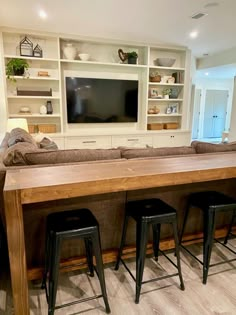 a living room filled with furniture and a flat screen tv mounted above a wooden table