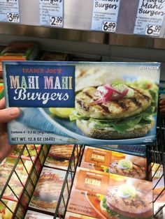 a person is holding up a menu for a burger in a grocery store's meat section